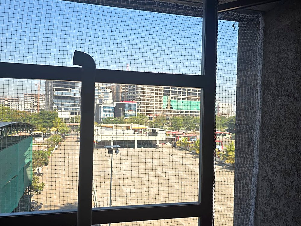 Pigeon net fitted on a high-rise balcony window in Vesu, Surat